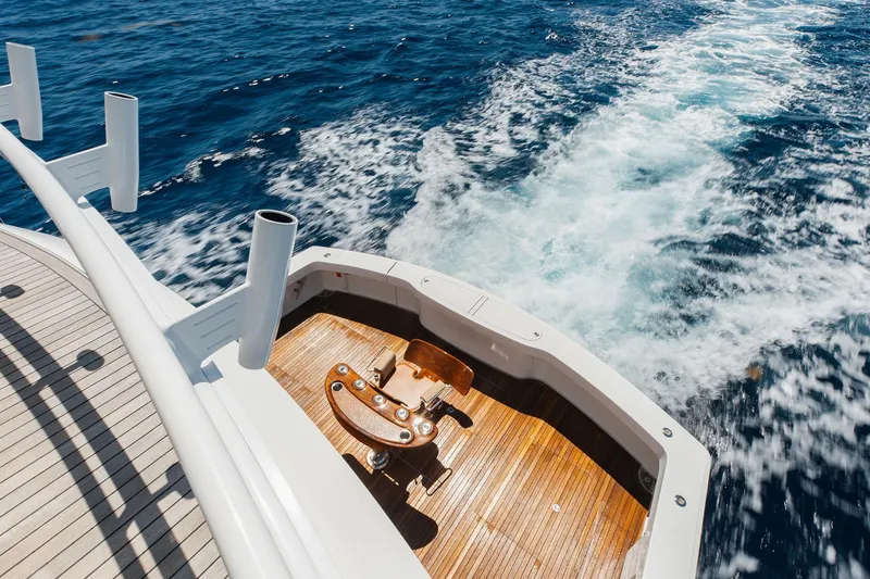 Slide: The Image of 2016 Viking 82 Sky Bridge yacht cruising on open sea, featuring wooden deck and fishing chair. - 8