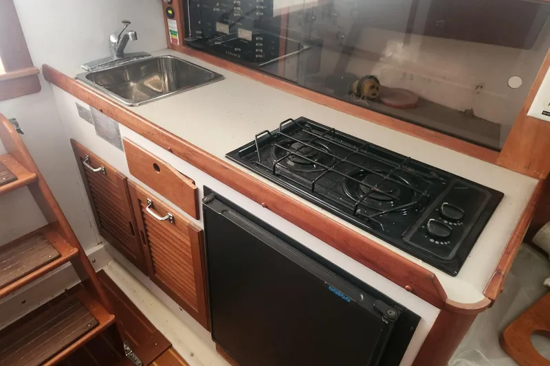 Slide: The Image of 2004 Legacy 28ft boat kitchen with stove, sink, and compact fridge. - 22