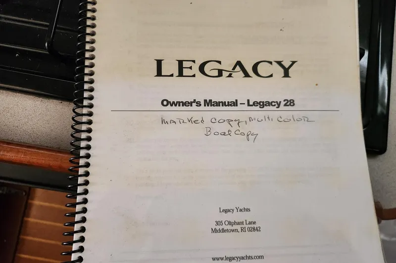 Slide: The Image of Owner's manual for 2004 Legacy 28ft yacht, spiral-bound with handwritten notes. - 27