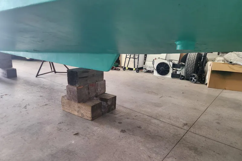 Slide: The Image of 2004 Legacy 28ft boat hull supported by wooden blocks in a garage. - 29