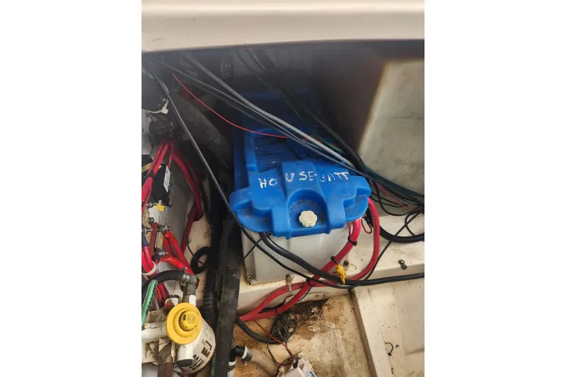 Slide: The Image of 2004 Legacy 28ft boat battery compartment with wiring and labeled blue battery. - 48