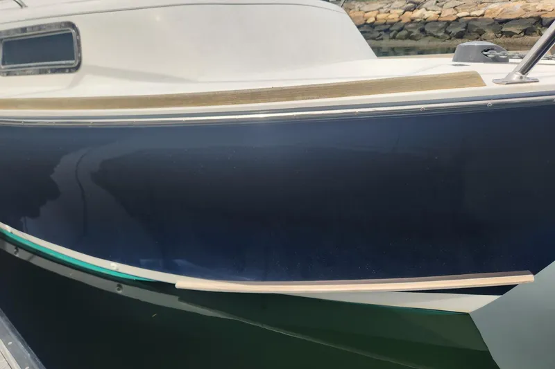 Slide: The Image of 2004 Legacy 28ft boat with sleek blue hull and wooden trim detail. - 7