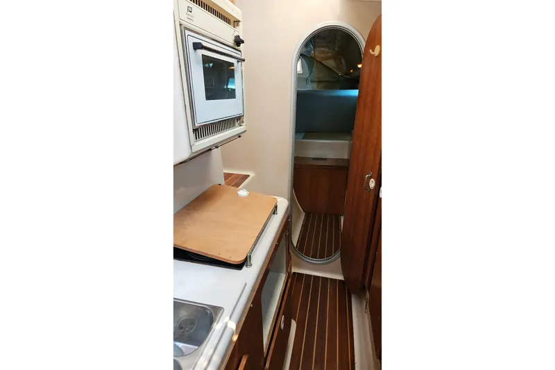 Slide: The Image of Interior of 1996 PDQ 32 LRC boat featuring compact kitchen and wooden cabinetry. - 23