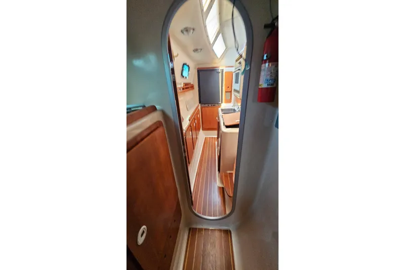 Slide: The Image of Interior view of 1996 PDQ 32 LRC boat, featuring wood paneling and compact kitchen area. - 27