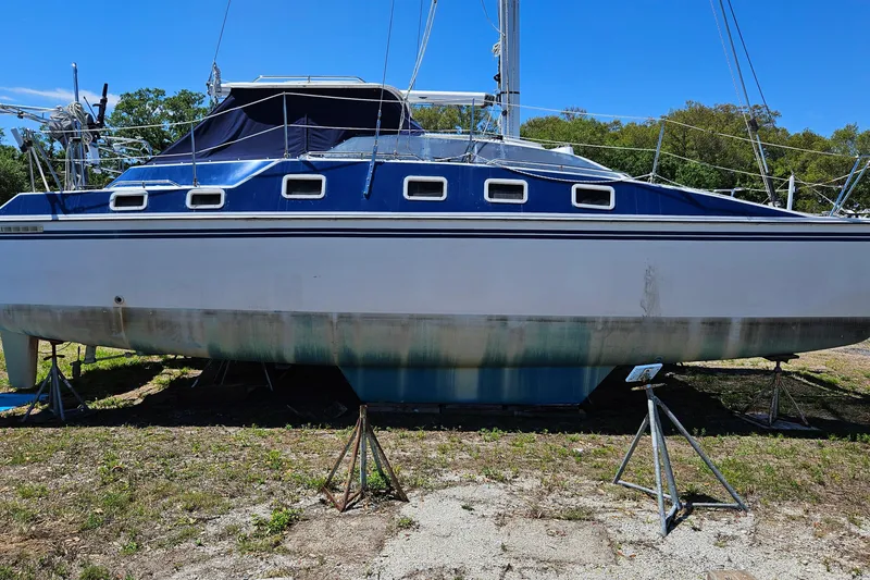 Slide: The Image of 1996 PDQ 32 LRC sailboat on land, supported by stands, under clear blue sky. - 8