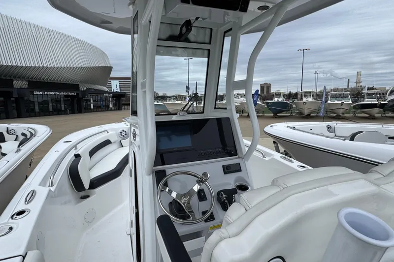 Slide: The Image of 2026 Tidewater 232 CC Adventure boat interior with modern helm and seating at a marina. - 8