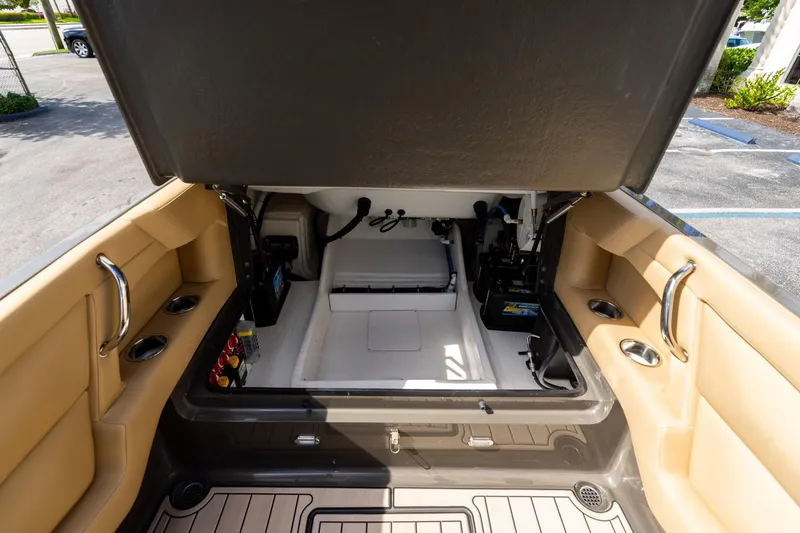 Slide: The Image of Open storage compartment in 2023 Airship 310 boat, featuring beige interior and cup holders. - 23