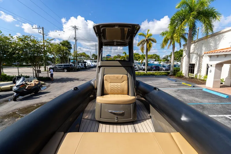 Slide: The Image of 2023 Airship 310 boat with tan seating, parked in a sunny lot with palm trees. - 38
