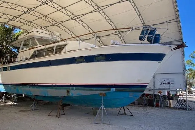 Slide: The Image of 1972 Chris-Craft boat under a large canopy, elevated on stands for maintenance. - 2