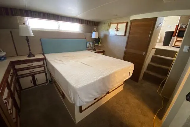 Slide: The Image of 1972 Chris-Craft boat interior with cozy bedroom, featuring a bed, lamps, and wooden cabinetry. - 21