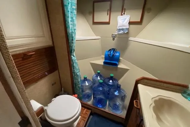 Slide: The Image of 1972 Chris-Craft boat bathroom with toilet, sink, and water jugs storage. - 26