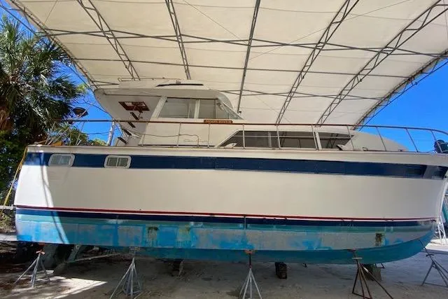 Slide: The Image of 1972 Chris-Craft boat under a canopy, elevated on stands, with blue and white hull. - 3