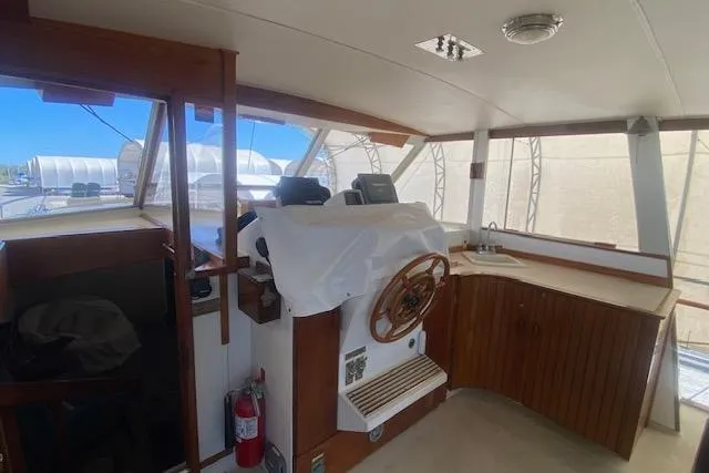 Slide: The Image of 1972 Chris-Craft boat interior with wooden helm, covered controls, and fire extinguisher. - 7