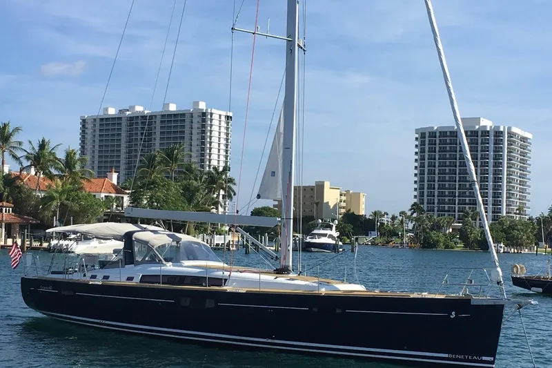 The Image of 2016 Beneteau Oceanis 60 yacht sailing near waterfront buildings and palm trees. - 0