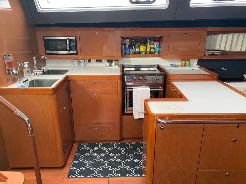 Slide: The Image of Interior of 2016 Beneteau Oceanis 60 yacht kitchen with wooden cabinetry and modern appliances. - 10