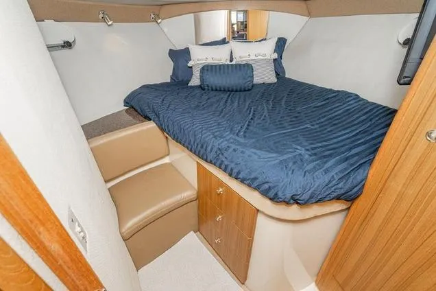 Slide: The Image of 2002 Bayliner 3488 Avanti cabin with blue bedding and wooden storage cabinets. - 17