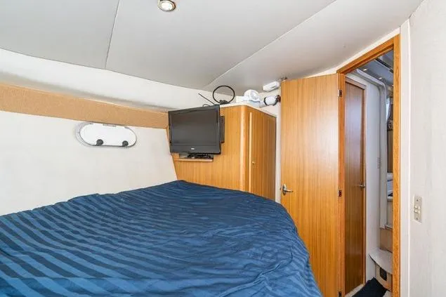 Slide: The Image of 2002 Bayliner 3488 Avanti cabin with bed, TV, and wooden door. - 18