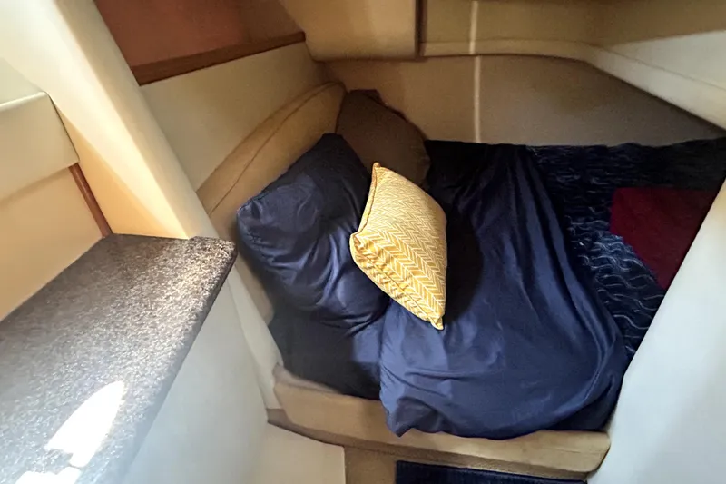 Slide: The Image of Cozy cabin interior of 2002 Bayliner 3488 Avanti with navy bedding and yellow pillow. - 31