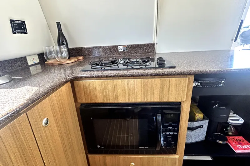 Slide: The Image of 2002 Bayliner 3488 Avanti kitchen with stove, microwave, and wine glasses on counter. - 38