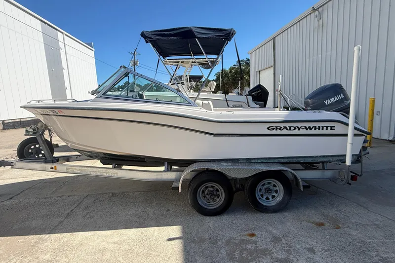 Slide: The Image of 1997 Grady-White Tournament 192 boat on trailer, parked outdoors near white buildings. - 3