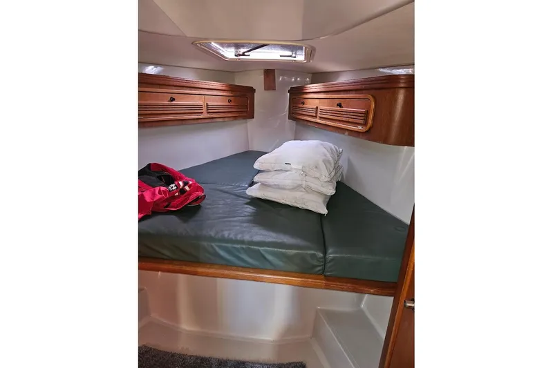 Slide: The Image of Cozy cabin interior of 2000 C&C 110 sailboat with green cushions and wooden storage. - 19