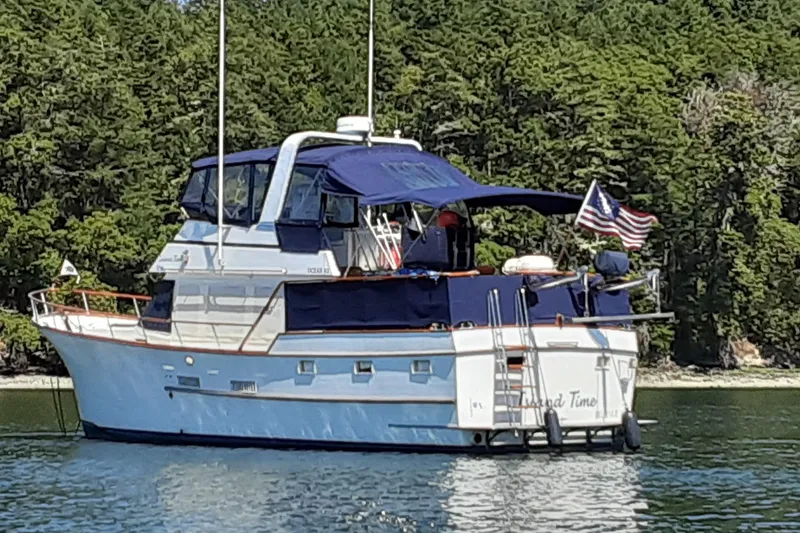 The Image of 1983 Ocean Alexander 43 Flush Aft Deck yacht anchored near lush forest. - 0