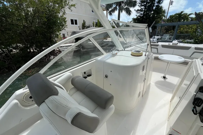 Slide: The Image of 2020 World Cat 296 DC boat interior with seating and table, surrounded by lush greenery. - 14