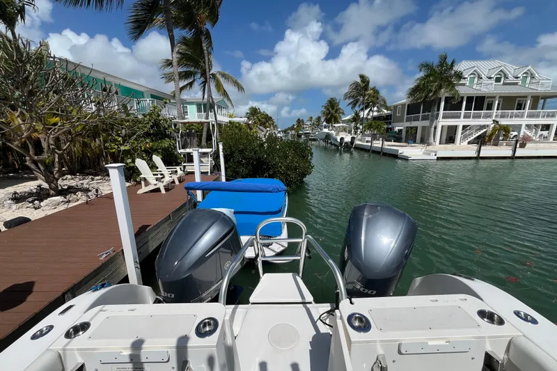 Slide: The Image of 2020 World Cat 296 DC boat docked by waterfront homes under a sunny sky. - 20