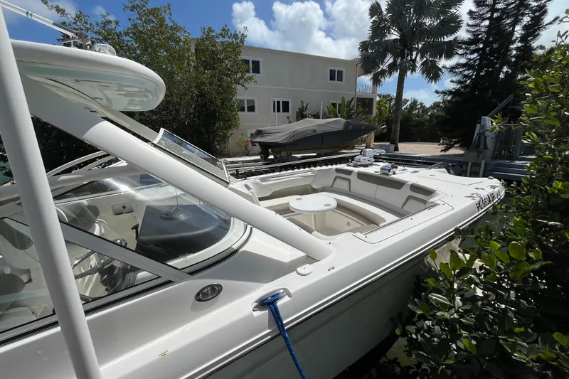 Slide: The Image of 2020 World Cat 296 DC boat docked near lush greenery and a residential building. - 4