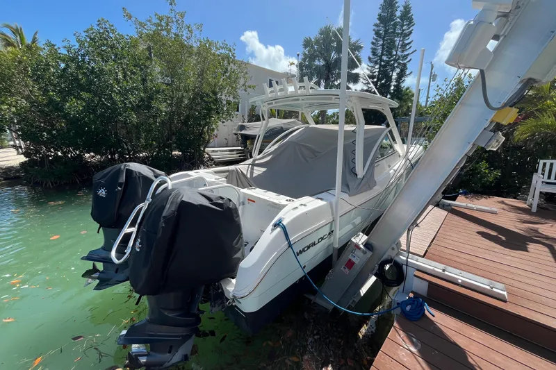 Slide: The Image of 2020 World Cat 296 DC boat docked with covered engines and lush greenery. - 5