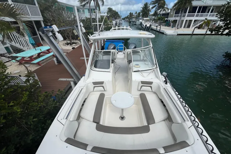 Slide: The Image of 2020 World Cat 296 DC boat docked by waterfront homes, featuring spacious seating and table. - 7