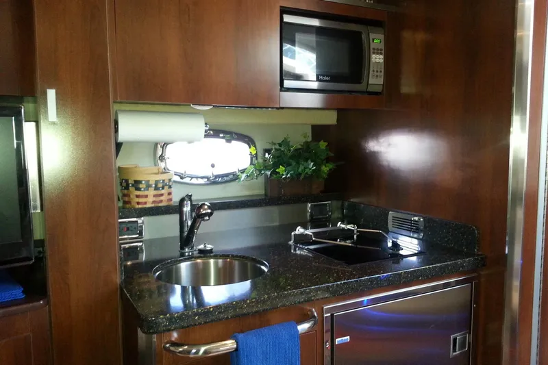 Slide: The Image of 2012 Chaparral 330 Signature yacht kitchen with microwave, sink, and wooden cabinetry. - 6