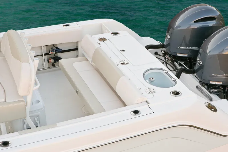 Slide: The Image of 2018 Robalo R242 Center Console boat interior with cushioned seating under a clear sky. - 10