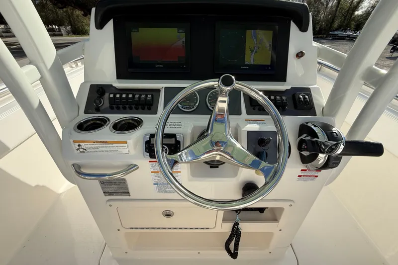 Slide: The Image of 2018 Robalo R242 Center Console boat dashboard with steering wheel and navigation screens. - 14