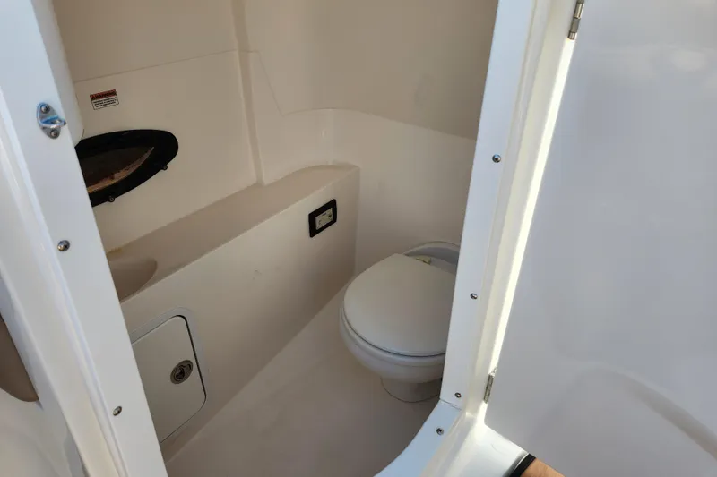 Slide: The Image of 2016 Hurricane SunDeck 2400 OB boat interior bathroom with toilet and storage. - 12