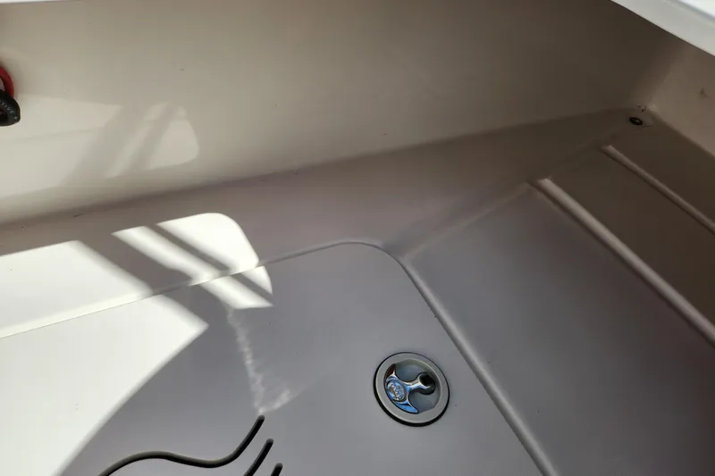 Slide: The Image of 2016 Hurricane SunDeck 2400 OB boat interior with drain plug and shadow details. - 34