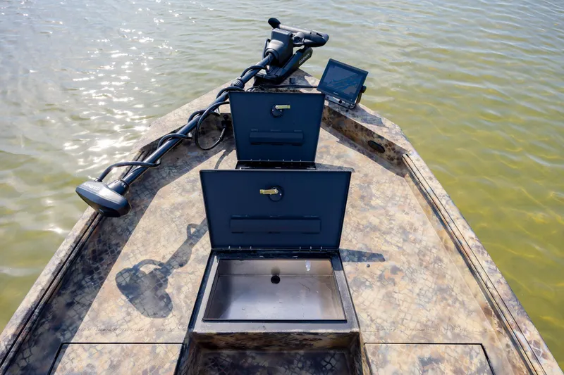 Slide: The Image of 2026 Excel 203 Bay Pro Elite boat with open storage compartments and trolling motor on water. - 11