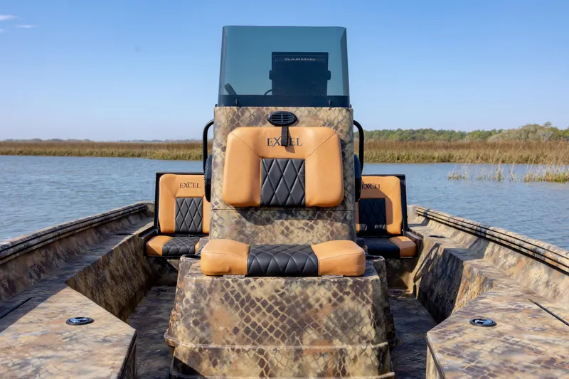 Slide: The Image of 2026 Excel 203 Bay Pro Elite boat with camo design and cushioned seating on a lake. - 20