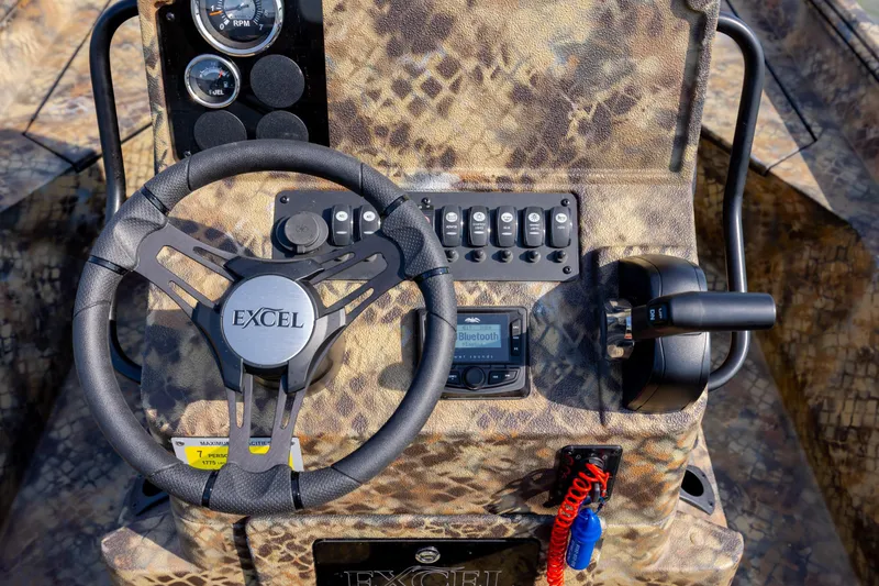 Slide: The Image of Steering console of 2026 Excel 203 Bay Pro Elite boat with camo design and controls. - 23