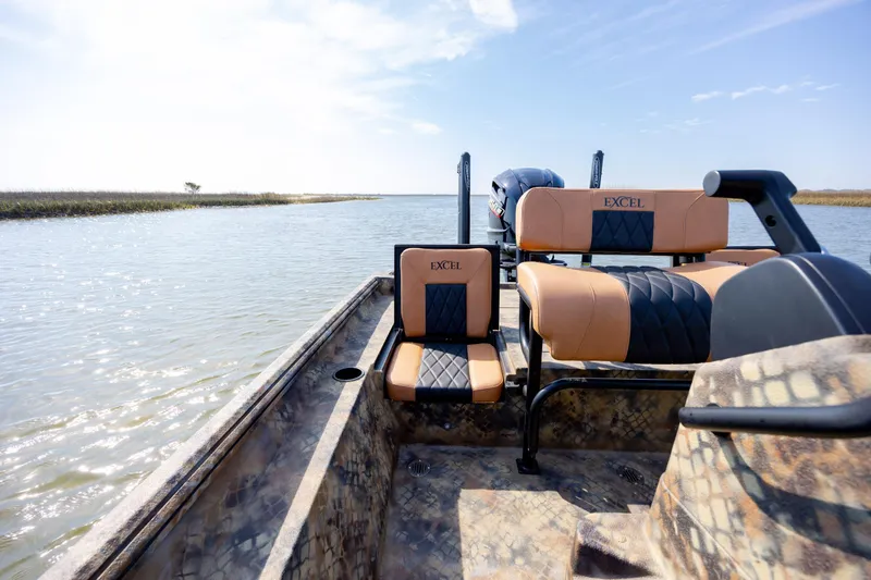 Slide: The Image of 2026 Excel 203 Bay Pro Elite boat interior with cushioned seats on a calm waterway. - 29
