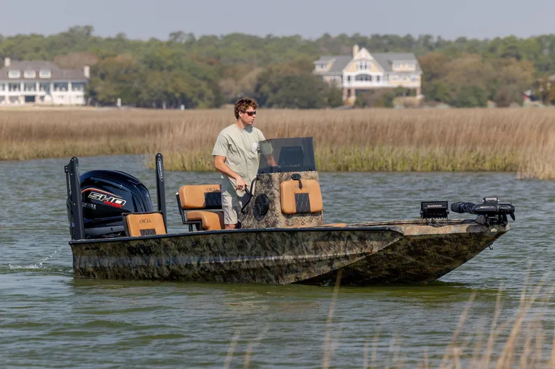 Slide: The Image of Man piloting 2026 Excel 203 Bay Pro Elite boat on a scenic waterway. - 4