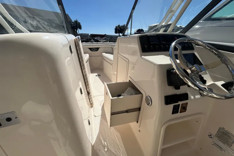 Slide: The Image of 2015 Grady-White Freedom 275 boat interior with steering wheel and open storage compartment. - 22