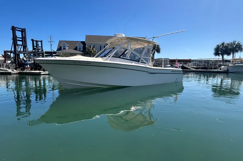 Slide: The Image of 2015 Grady-White Freedom 275 boat docked in a marina under clear blue skies. - 3