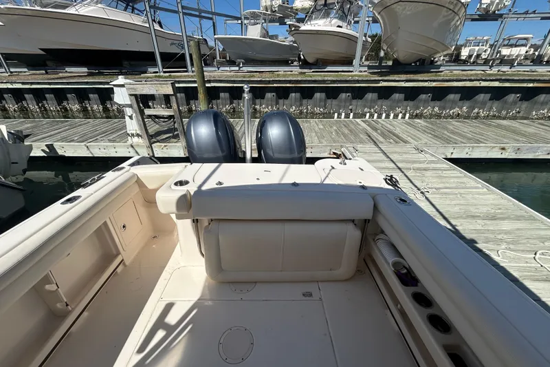 Slide: The Image of 2015 Grady-White Freedom 275 boat docked, showcasing spacious deck and dual engines. - 6