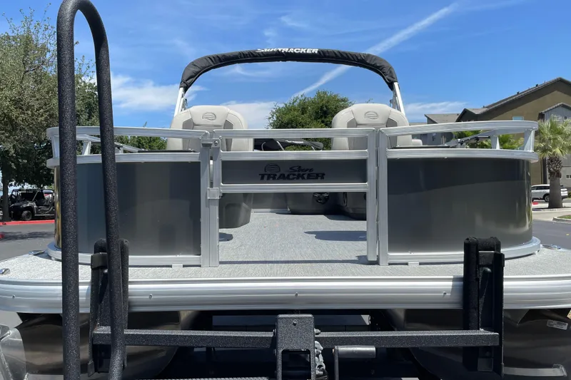 Slide: The Image of 2026 Sun Tracker Bass Buggy 16 XL Select pontoon boat on trailer, parked outdoors. - 5