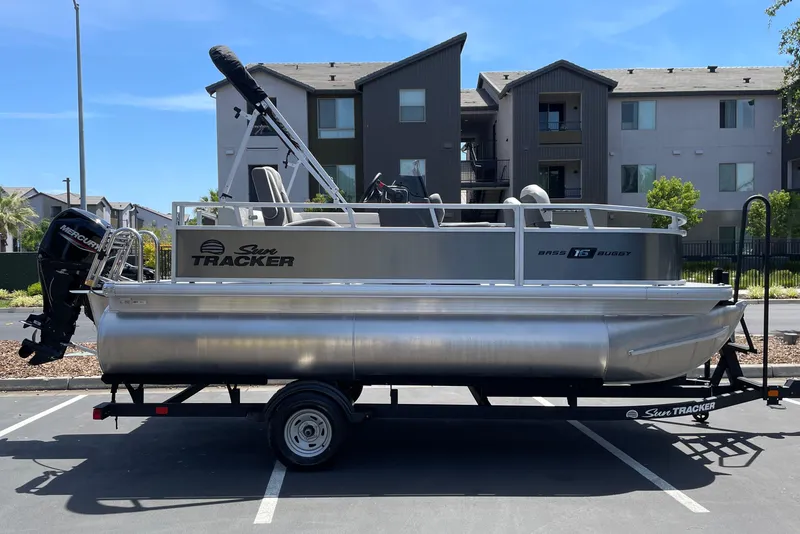The Image of 2026 Sun Tracker Bass Buggy 16 XL Select pontoon boat on trailer in parking lot. - 0