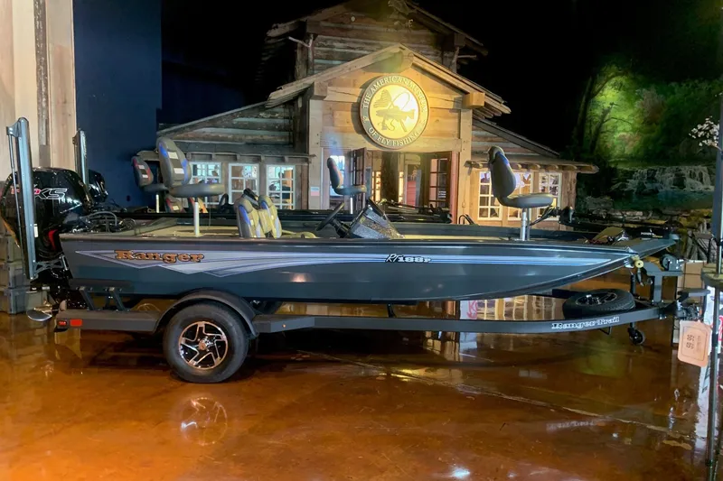 The Image of 2026 Ranger RT188P fishing boat displayed indoors with rustic cabin backdrop. - 0
