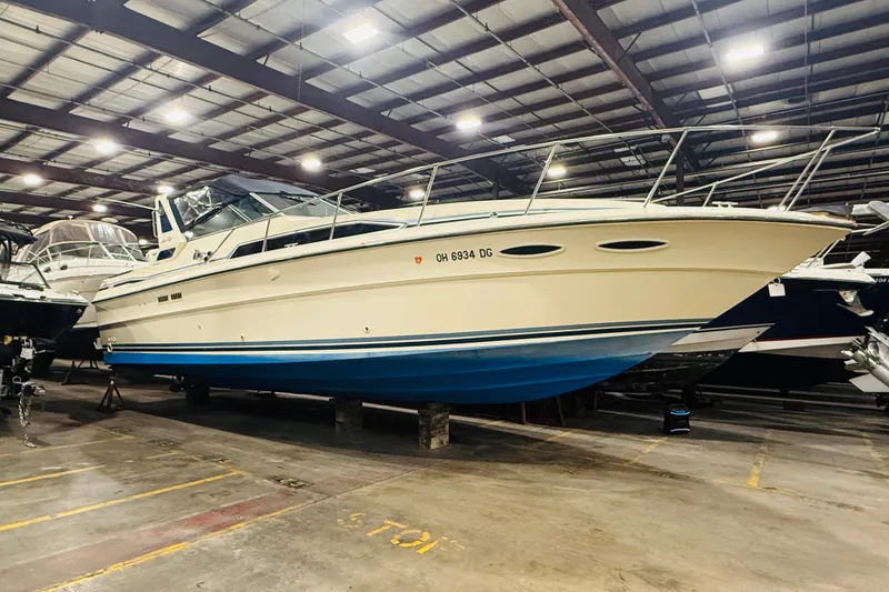 The Image of 1986 Sea Ray 340 Express Cruiser in indoor storage, showcasing sleek design and blue hull. - 1