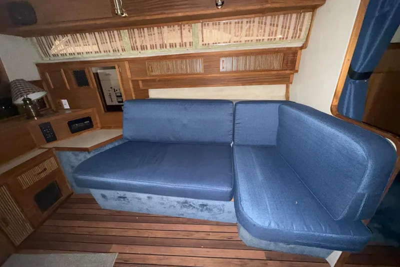 Slide: The Image of Interior of 1986 Sea Ray 340 Express Cruiser with blue sofa and wooden accents. - 13