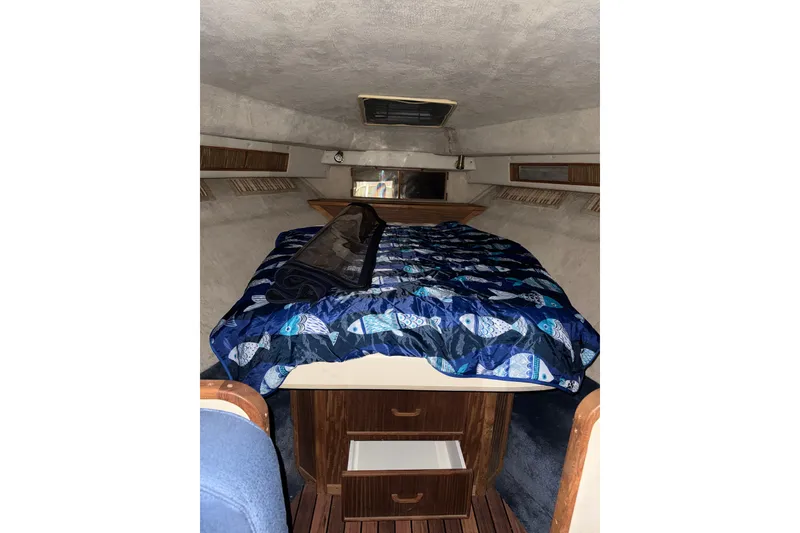 Slide: The Image of 1986 Sea Ray 340 Express Cruiser cabin with fish-patterned bedding and wooden storage. - 14